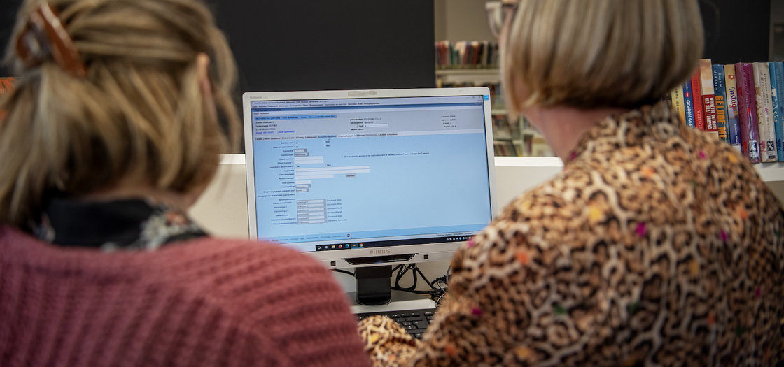 2 bibliotheekmedewerkers zijn bezig met klantenadministratie op een scherm in Wise