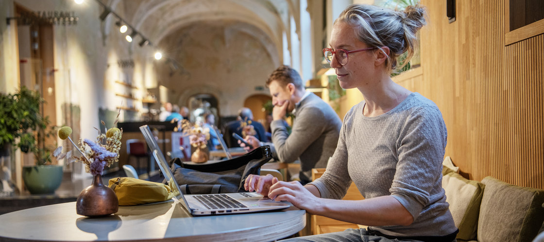 Vrouw werkt aan computer in de werkzaal van de bib.