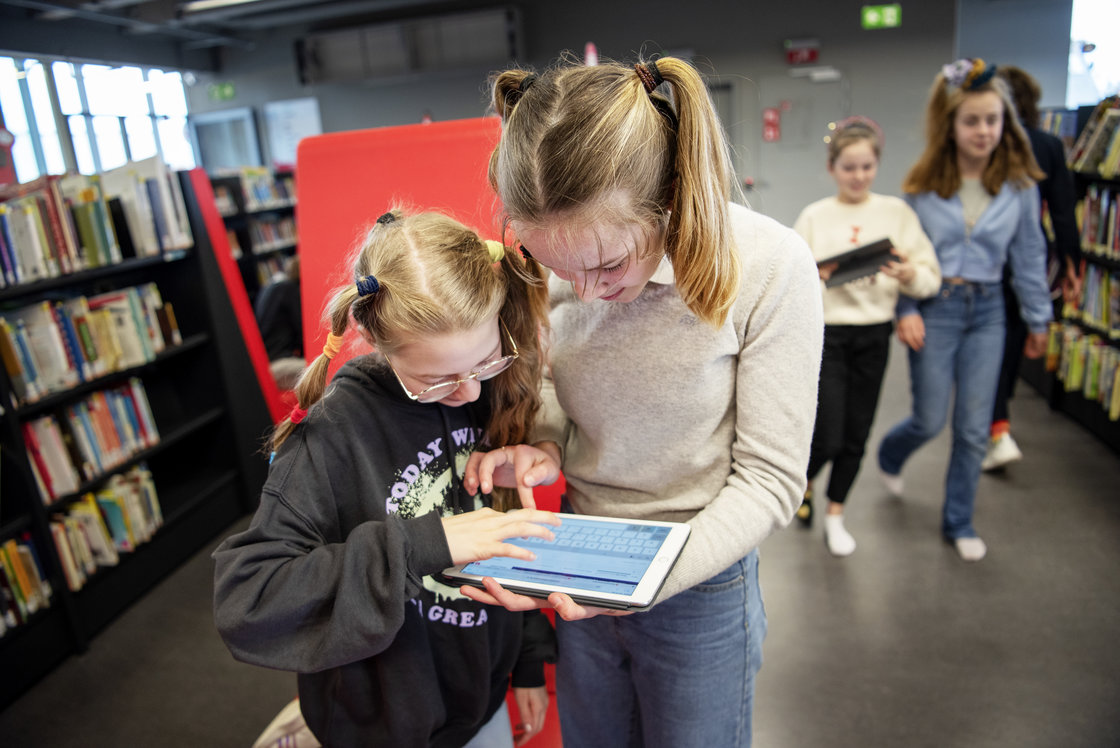 Leerlingen op een tablet in de bib aan het zoeken 