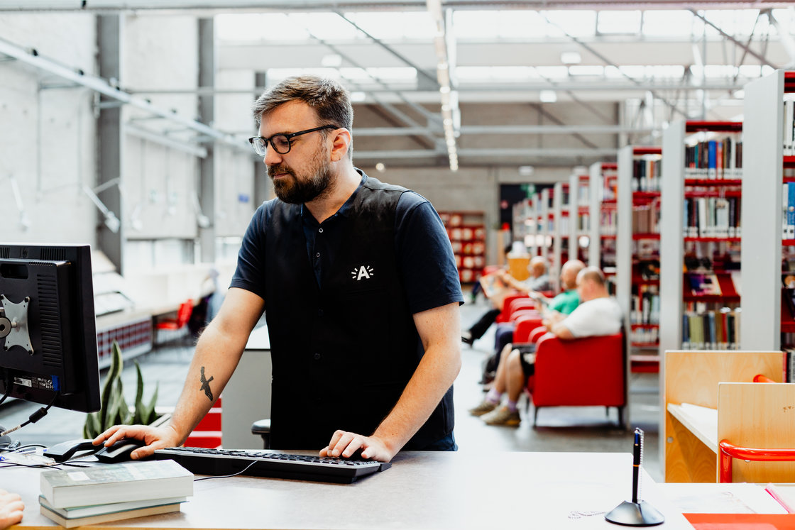 Foto van een medewerker van de bib aan een computer