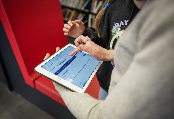 2 personen (onherkenbaar) raadplegen de catalogus van de bibliotheek van Roeselare.