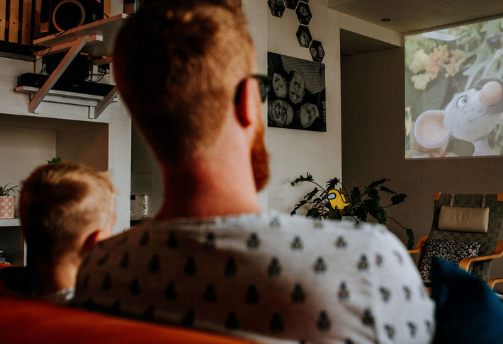 Gezin kijkt naar een familiefilm op groot scherm in de woonkamer.