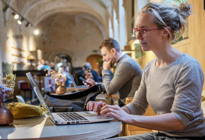 Vrouw werkt aan computer in de werkzaal van de bib.