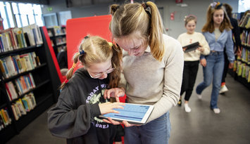 Leerlingen op een tablet in de bib aan het zoeken 